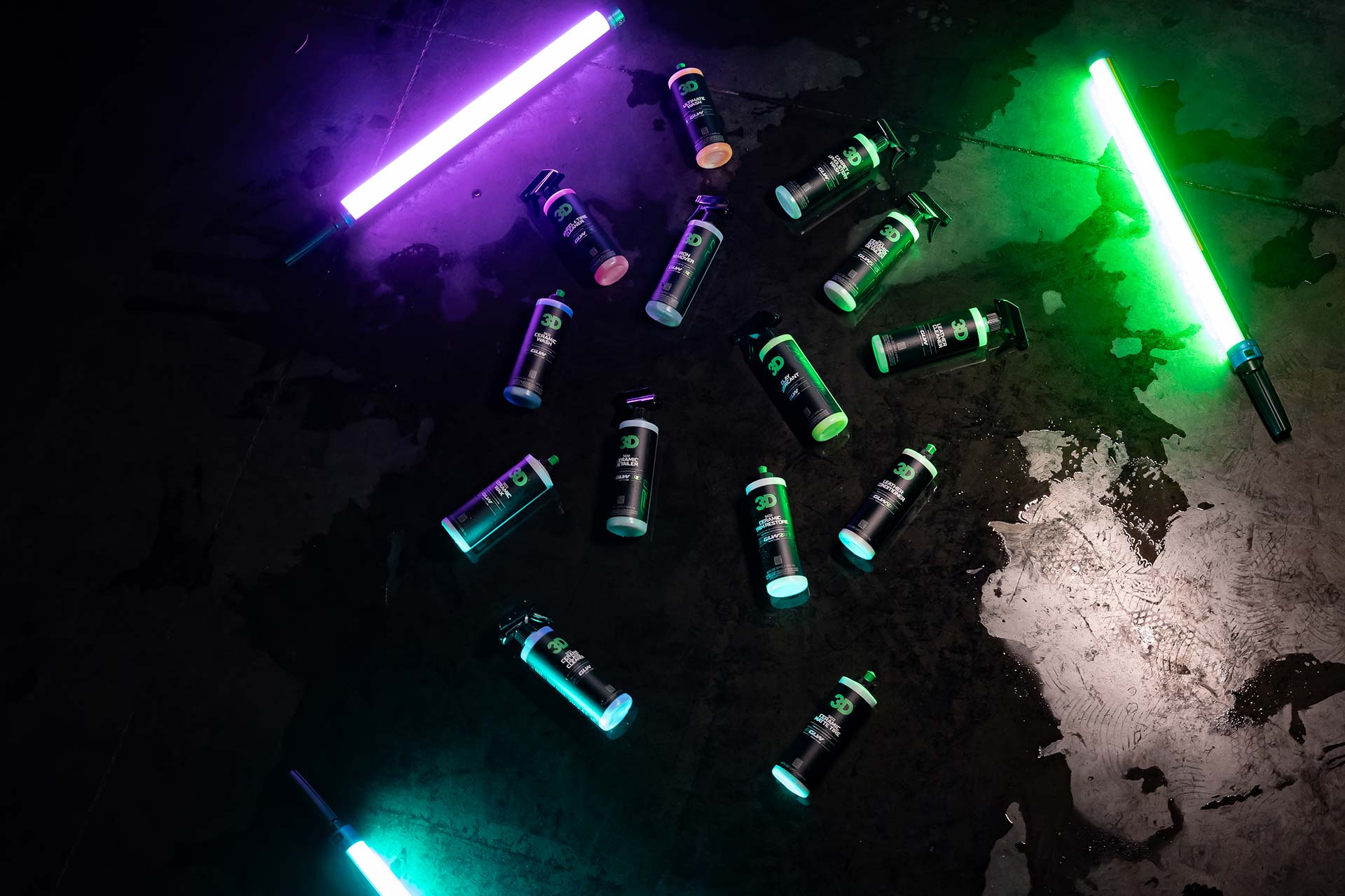 top down shot of 3d car care glw series products on dark warehouse floor with colorful lighting