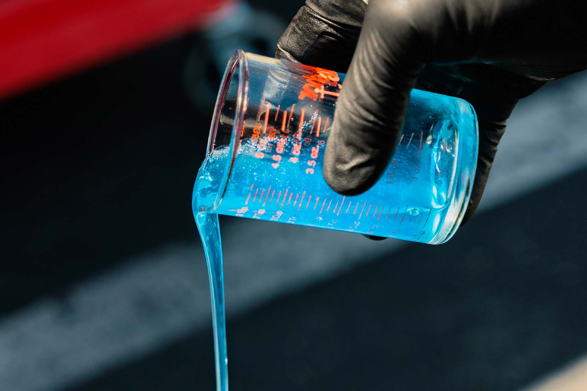 detailer using a measuring glass pouring car wash soap