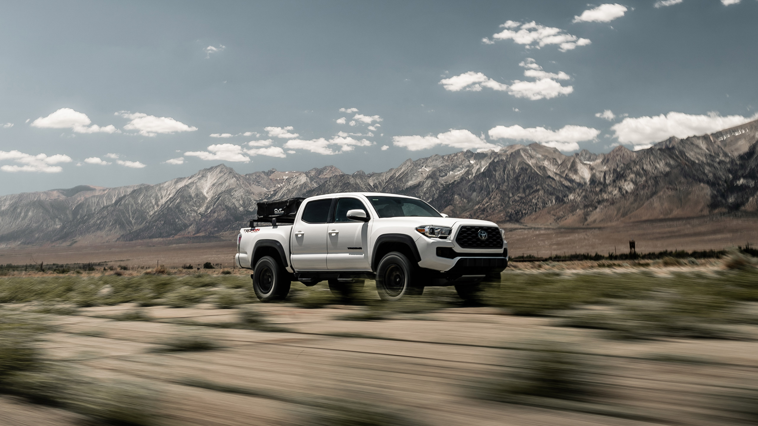 white toyota tacoma driving through desert