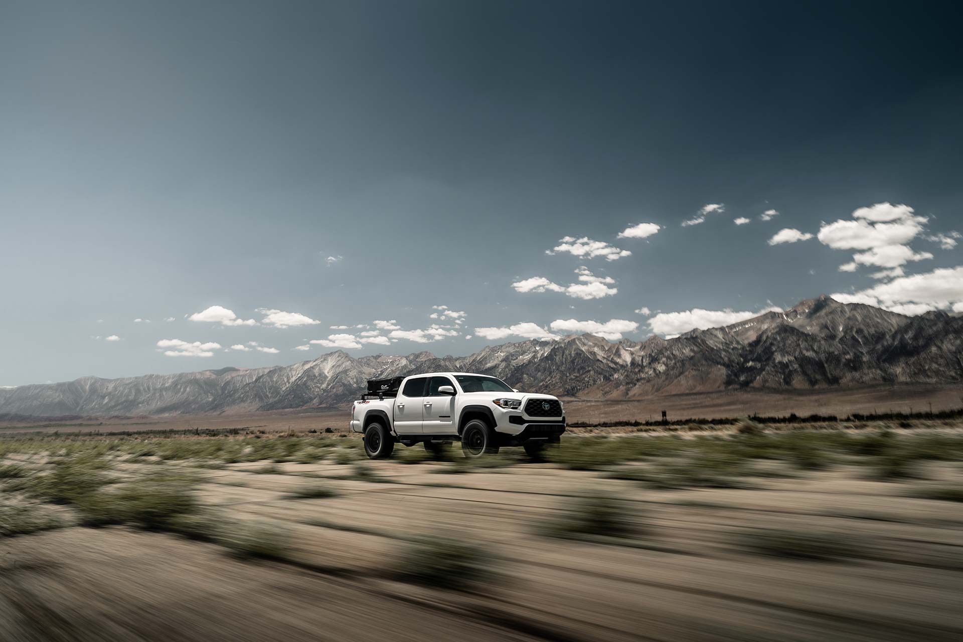 white toyota tacoma with rbp tires driving at high speeds through desert